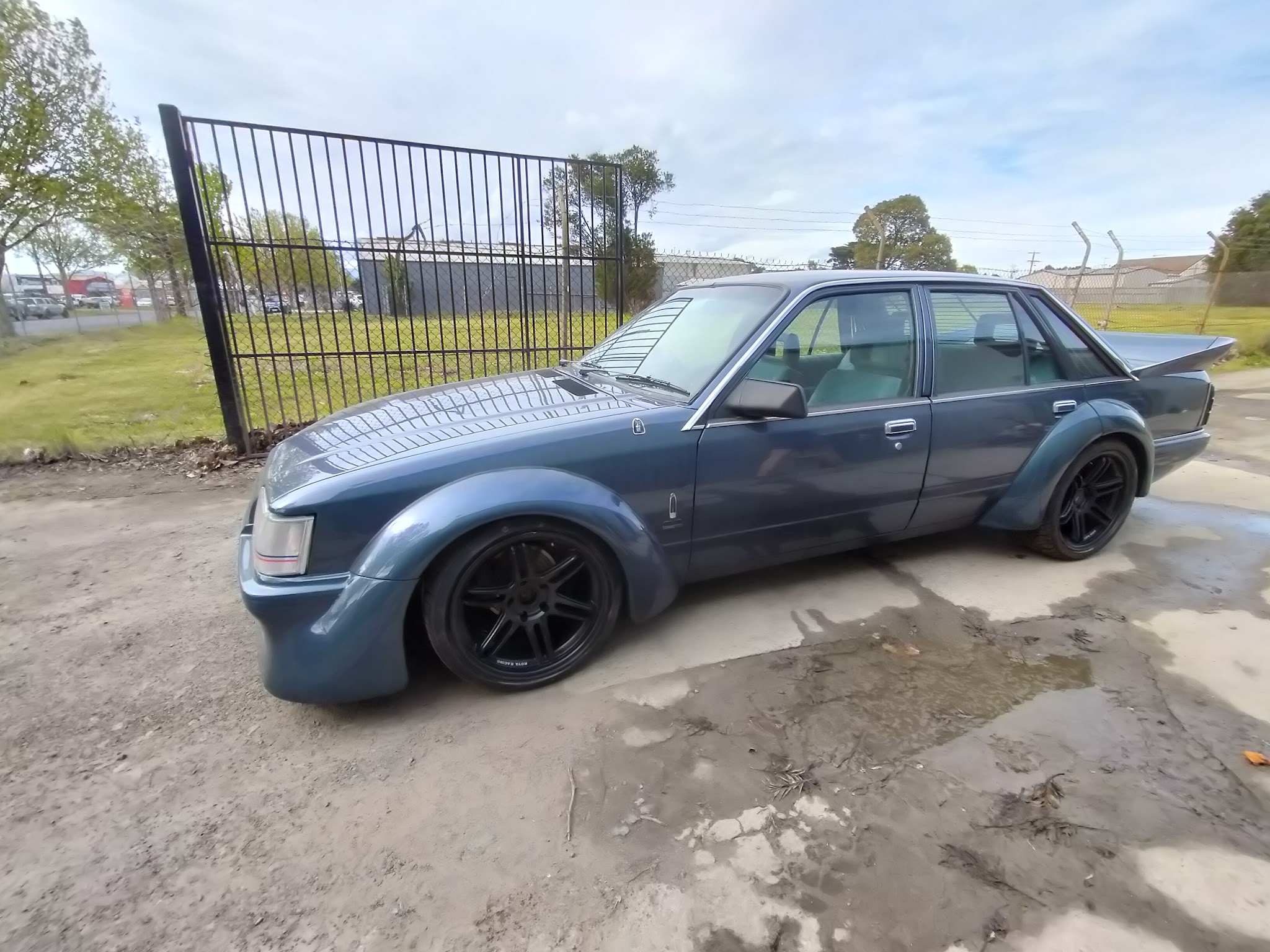A blue grey Falcon sedan on flared guards and black rims, finished