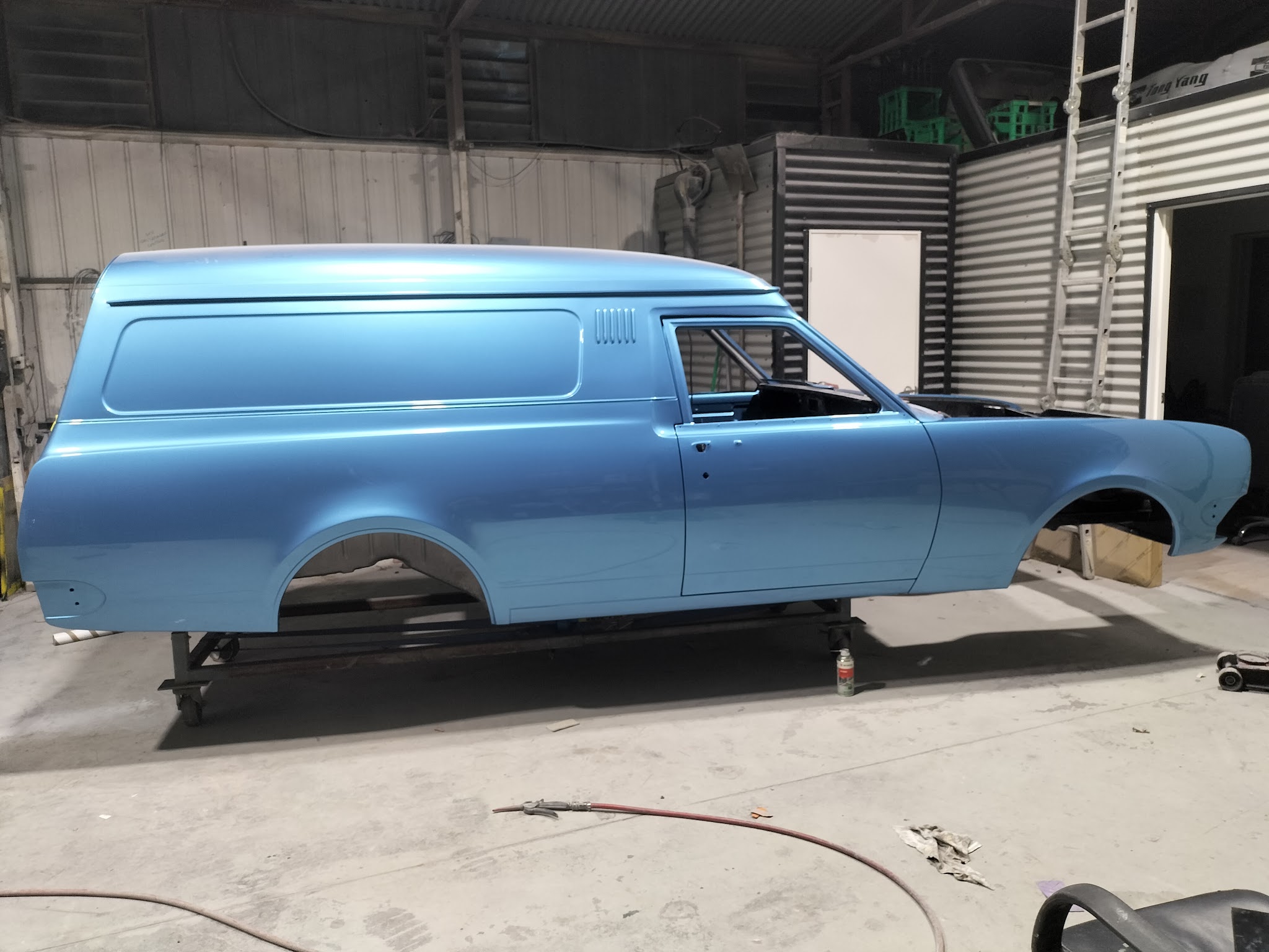 A Holden panel van shell in fresh light blue metallic, on a rolling frame in the workshop